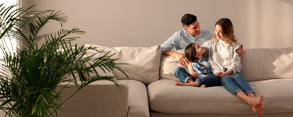Familie - far, mor og datter sidder trygt i sofa med Familie360.